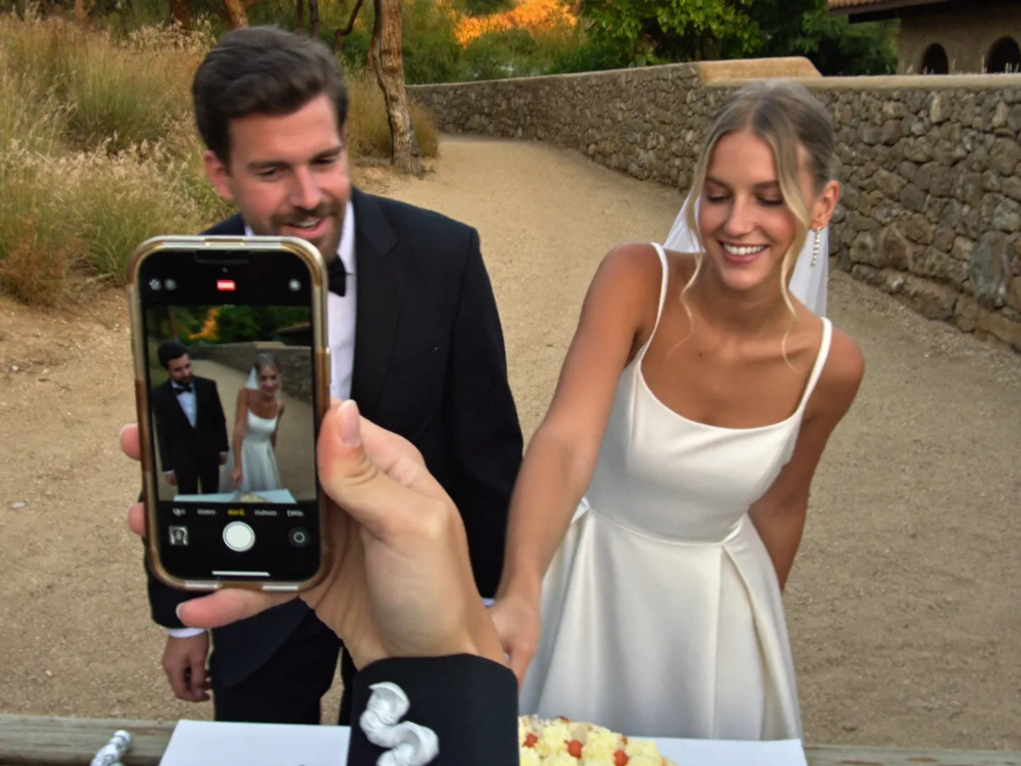 Una invitada fotografía a la pareja cortando la tarta