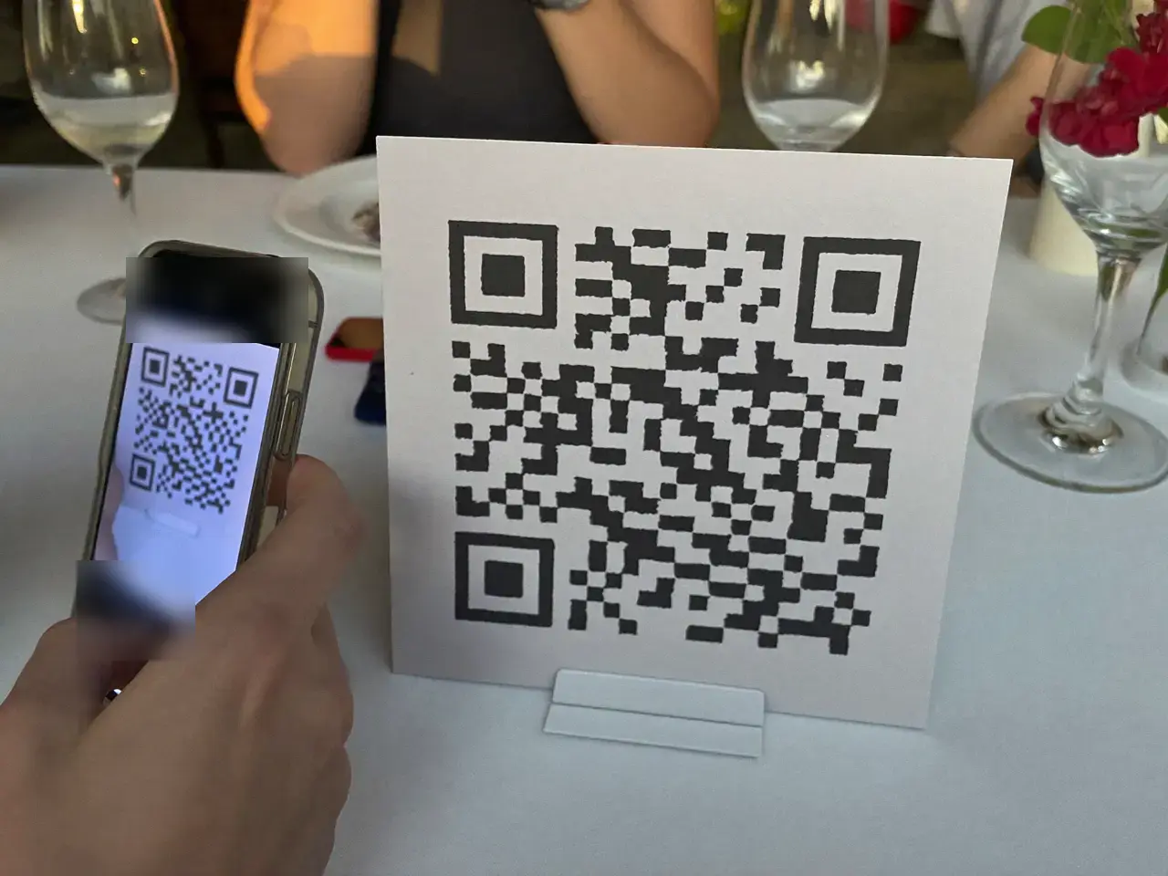 Una mano escanea el código QR de la tarjeta en la mesa del banquete